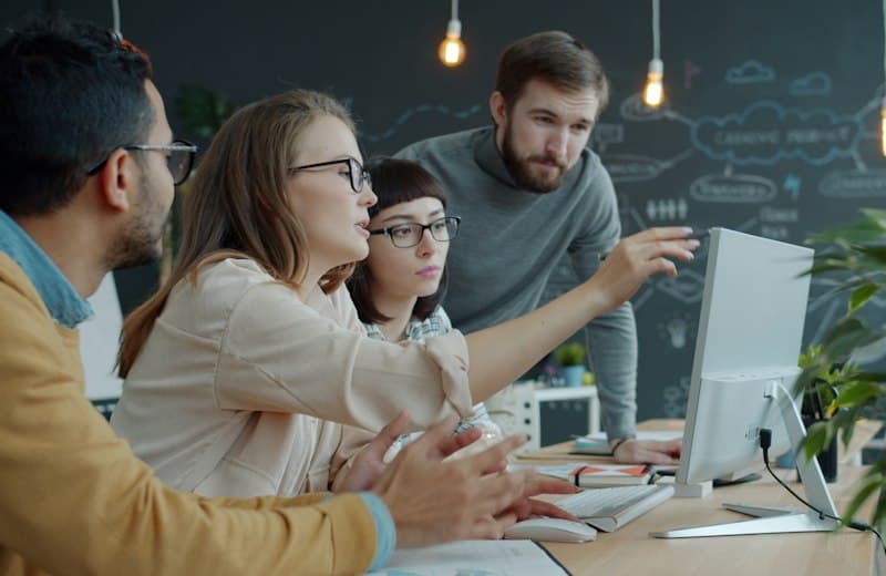 Equipo de trabajo revisando información juntos frente a una computadora